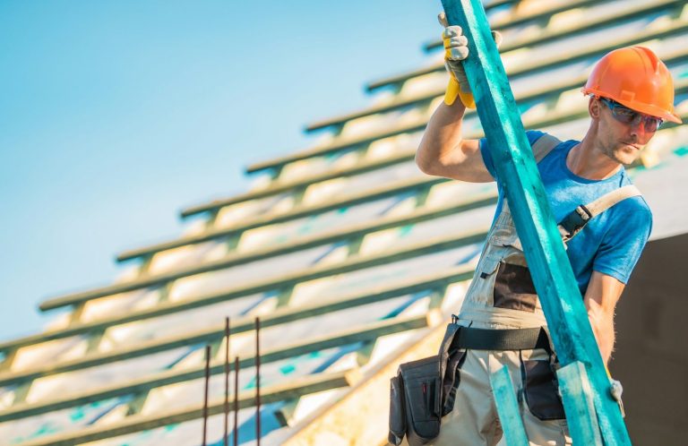 Dachdecker mit Helm arbeitet auf einem Dachstuhl